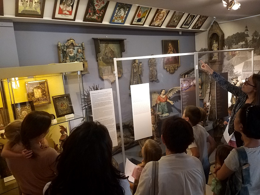 dzieci z rodzicami zwiedzają wystawę w Muzeum Etnograficznym, oglądają obrazy