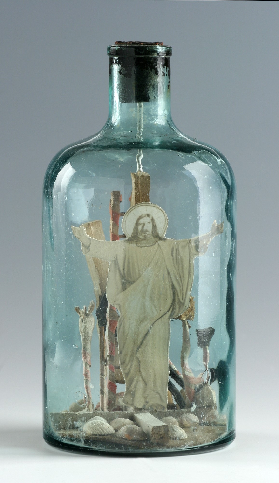w butelce z białego szkła znajduje się grafika ze Zmartwychwstałym Chrystusem
