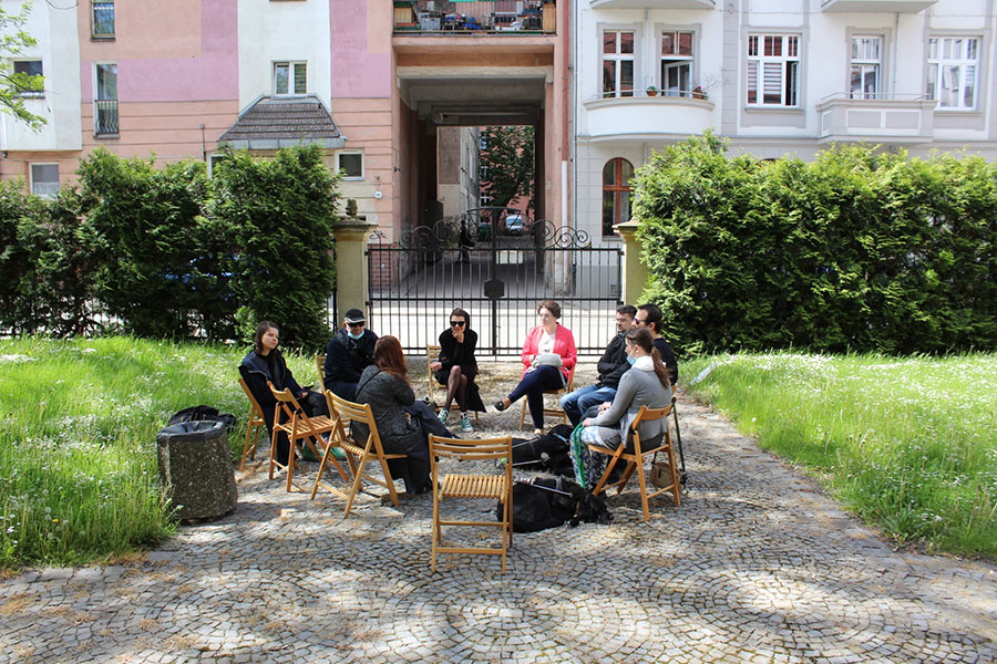 Spotkanie przy Muzeum Etnograficznym – zebrani siedzą na krzesłach w muzealnym ogrodzie