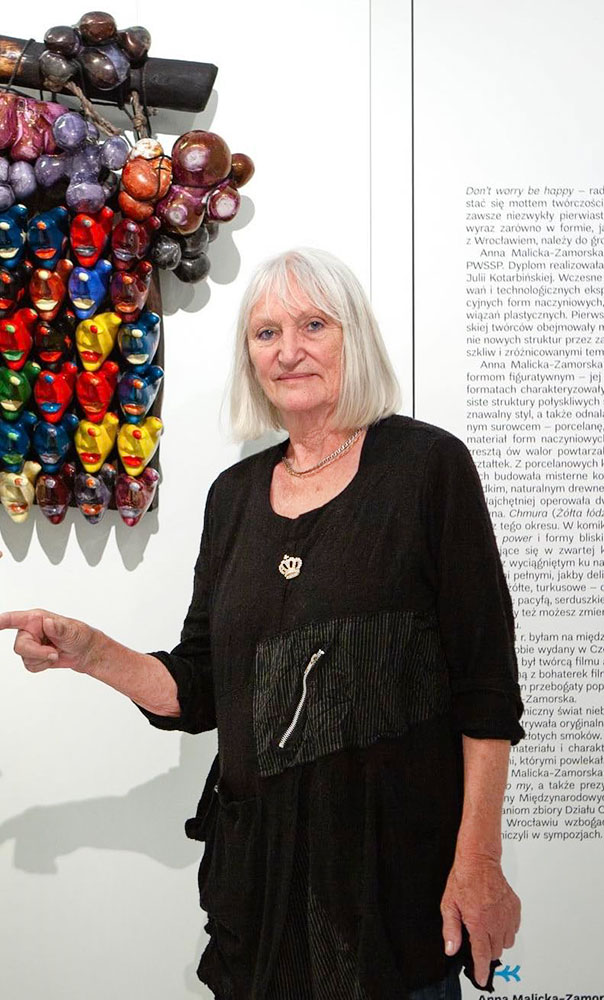 Portret Anny Malickiej-Zamorskiej na tle jej ceramicznej rzeźby w kształcie kolorowych dłoni-twarzy